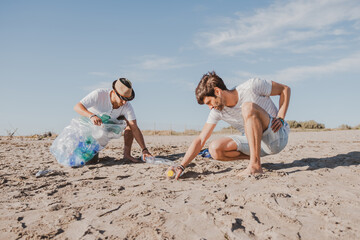 Group of activist friends collecting plastic waste on the beach. People cleaning the beach, with...