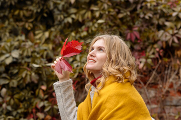 A young adult blonde woman walk in the autumn park in fall
