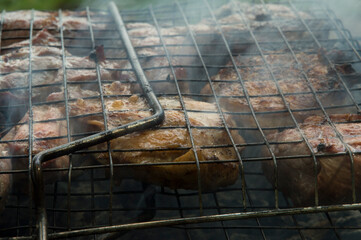 close-up: roast porkmeat inside grill on fire with smoke