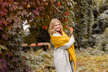 A young adult blonde woman walk in the autumn park in fall
