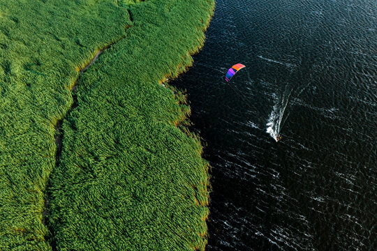 Aerial view of person with kite kiteboarding in wild lagoon in Lithuania.