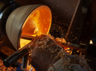 A wooden bowl being turned by a man on a woodturning lathe.A craftsman at work.Sawdust is flying.