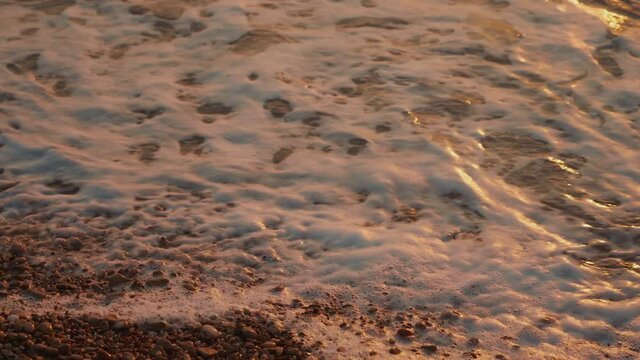4k closeup footage of sea waves wahing off footprints on the golden sand at beach

