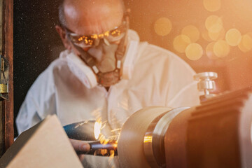 Obraz premium A wooden bowl being turned by a man on a woodturning lathe.A craftsman at work.Sawdust is flying.