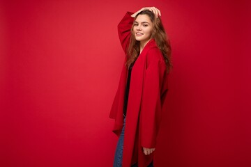 Fototapeta premium Photo of young attractive caucasian hipster woman in trendy casual clothes. Sexy carefree female person posing isolated near red wall in studio. Positive model with natural makeup. Empty space