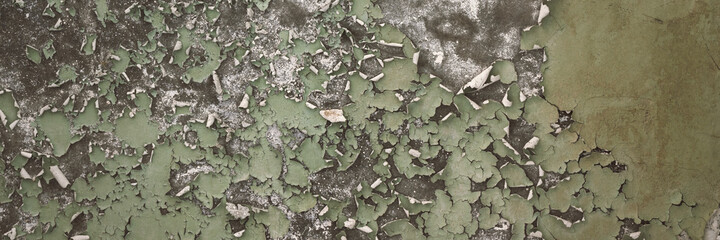 Peeling paint on the wall. Panorama of a concrete wall with old cracked flaking paint. Weathered rough painted surface with patterns of cracks and peeling. Grunge texture for wide panoramic background