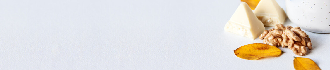 Banner of white chocolate nuts white cup and gold autumn leaves on bright background with copy...