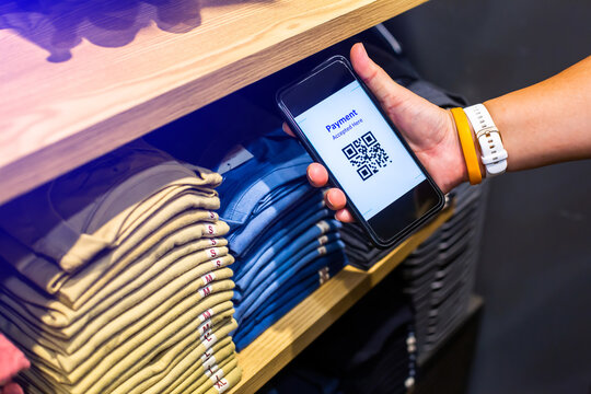 Selective focus to payment QR code tag on smartphone with blurry many clothes in the store to accepted generate digital pay without money. Qr code payment concept.