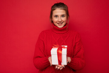 Shot of attractive positive smiling young brunette woman isolated over colourful background wall wearing everyday trendy outfit holding gift box and looking at camera