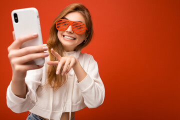 Closeup portrait of attractive positive smiling young blonde woman wearing stylish white hoodie and...