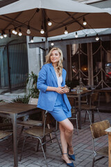 Beautiful woman businesswoman in a blue suit with a smartphone in her hands, teleworking. Soft selective focus.
