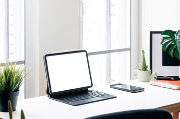 Fototapeta na wymiar Creative workspace with blank screen tablet and gadget on wooden table in modern white room.