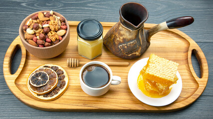 fresh hot coffee with turkey and dried citrus, nuts and honeycomb on a kitchen wooden board. useful vitamin food for the human body