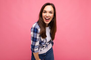 Young beautiful brunet woman. Trendy lady in casual summer hipster shirt . Positive female shows facial sincere emotions. Funny model isolated on pink background with free space
