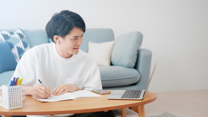 ノートパソコンでオンライン授業を受ける男性