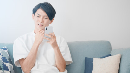 ソファーでスマートフォンを使う男性