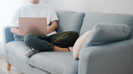 ソファーの上でノートパソコンを使う男性