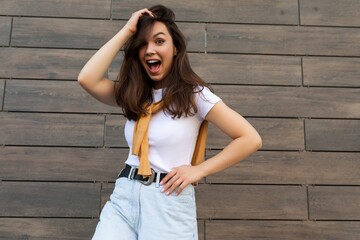 Shot of emotional positive happy joyful pretty young brunette woman in trendy outfit. Beautiful attractive female person standing outside in the street and showing sincere emotions