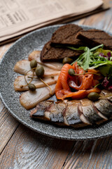 Close up of assorted fish delicatessen: smoked cod, marinated herring, smoked salmon and rye toasts
