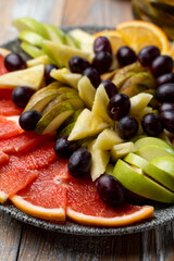 A stone dish filled with ripe tropical fruits as a wine snack in a winery