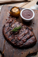 Gourmet loin steak in a fancy restaurant, dark roasted meat with bbq sauce, dark wooden cutting board, top view