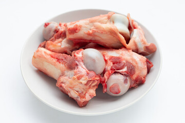 Raw pork bones in white plate on white background.
