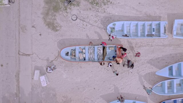 Group Of Local Fishermen Around Wooden Fishing Boat Wih Freshly Caught Fish. - aerial top