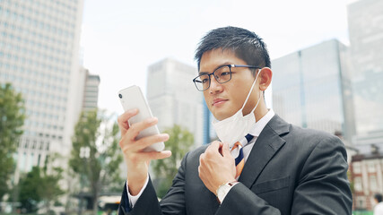 マスクを外してスマホの顔認証をする男性