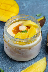 Mango ice cream sorbet with mint leaves and fresh mango served in a glass jar. italian dessert gelato