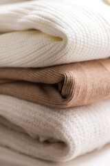 Fototapeta na wymiar Folded knitted beige and white sweaters. Autumn and winter wardrobe concept