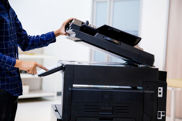 Businessmen press button on the panel for using photocopier or printer for printout and scanning document paper at office.
