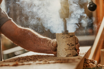 Carpenter creating a cloud of smoke drilling through wood