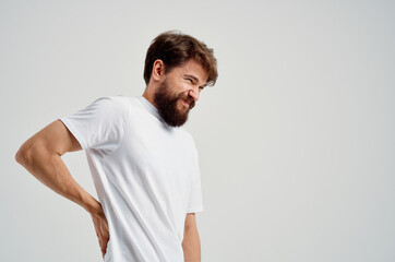 emotional man in a white t-shirt stress medicine backache light background