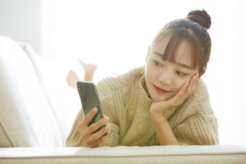 自宅でスマートフォンを操作する若い女性
