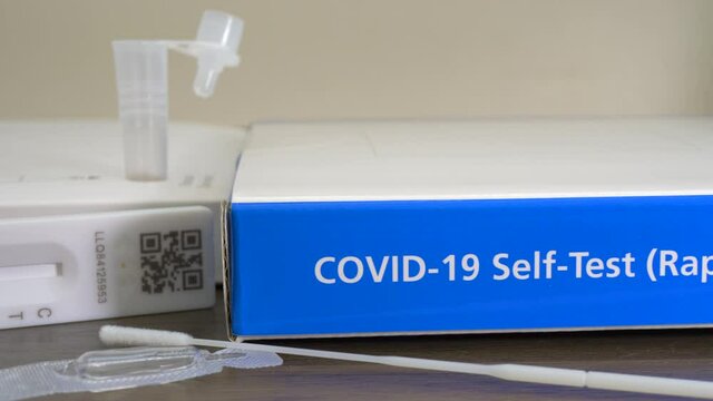 Closeup POV dolly shot of an unbranded Covid-19 rapid antigen, self-test kit, with the contents of one test laid out on a table, ready to be used.