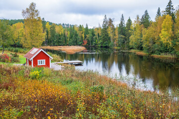 Forest lake with a red cottage by a bathing place