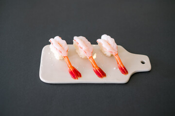 Prawn sushi in japanese restaurant. Sushi - ama Ebi Nigiri on white board isolated on black...