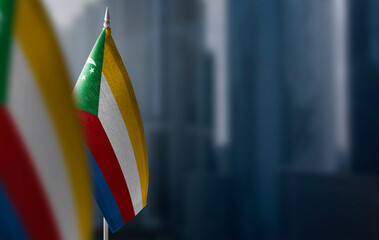 Small flags of Comoros on a blurry background of the city