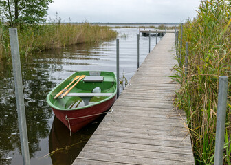 Fototapeta premium the wooden footbridge on the lake shore, fishing boats
