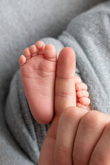 The father is holding the feet of the newborn baby. grey colour. tenderness. Father's day concept.