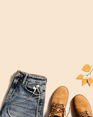 Autumn warm clothes flat lay, fashion red shoes, knitted sweater or turtleneck, blue jeans isolated on beige pastel color