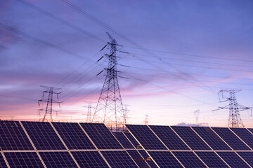 Transmission towers and solar panels are clean energy concepts. Sunset background