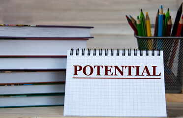 POTENTIAL - word in a notebook against the background of books and pencils
