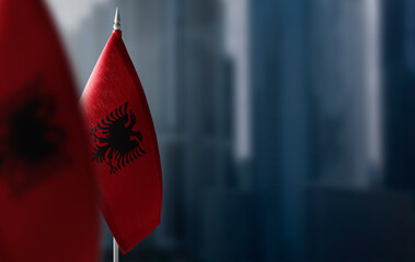 Small flags of Albania on a blurry background of the city