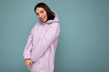 Fototapeta premium Young cute sttractive brunette woman with sincere emotions isolated on background wall with copy space wearing stylish purple hoodie. Happy cute concept