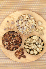 Gold frankincense and myrrh in bowls and loose on a wooden board. Symbols of gifts in the Christian religion given to Jesus Christ at his birth by the Three Wise Men. On bamboo background.