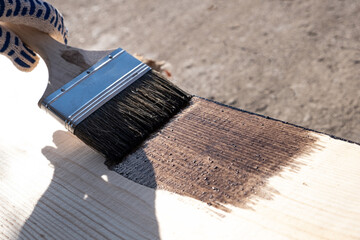 Painting a wooden board outdoors. Coated with protective oil against decay and moisture.