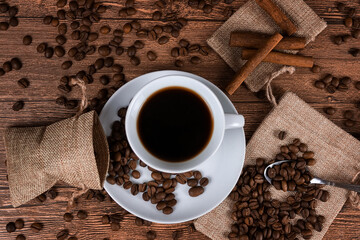 Black coffee foil packaging bag on wooden table top view. Spilled beans flat lay concept. Room for text