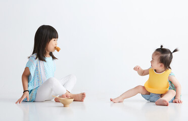 Cute Asian little sisters are eating, indoor