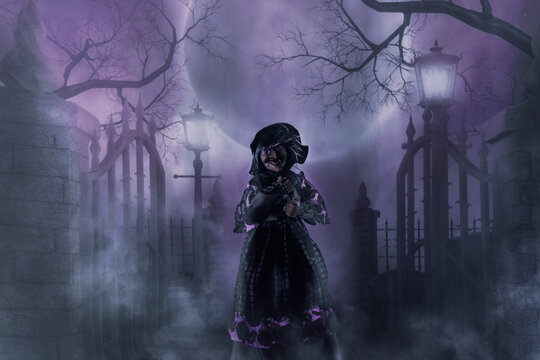 Witch in front of graveyard fence